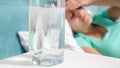 Closeup image of aspiring painkiller dissolving in glass of water on bedside table