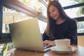 Closeup image of a beautiful Asian business woman looking , working and typing on laptop keyboard with white coffee cup on table Royalty Free Stock Photo