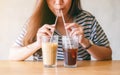 A beautiful asian woman drinking two glasses of iced coffee with stainless steel straws at the same time Royalty Free Stock Photo