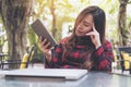 A beautiful Asian woman with feeling tired , close her eyes and holding tablet pc with laptop on glass table sitting at outdoor Royalty Free Stock Photo