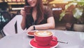 Closeup image of a beautiful Asian woman holding and drinking coffee with latte coffee cup on glass table Royalty Free Stock Photo