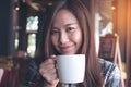 Closeup image of a beautiful Asian woman holding and drinking hot coffee with feeling good
