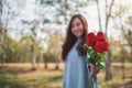 A beautiful asian woman holding and giving red roses flower on Valentine`s day