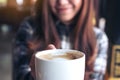 Closeup image of a beautiful Asian woman holding and showing a white mug while drinking hot coffee with feeling good Royalty Free Stock Photo