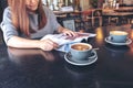 A beautiful asian woman reading magazine with coffee cup on table in modern cafe Royalty Free Stock Photo