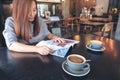 A beautiful asian woman reading magazine with coffee cup on table in modern cafe Royalty Free Stock Photo