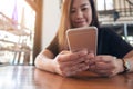 Closeup image of a beautiful Asian woman with smiley face holding and using smart phone Royalty Free Stock Photo