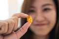 A beautiful Asian woman smiling , holding and looking at orange gummy bear