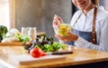 A beautiful female chef cooking and holding a bowl of fresh mixed vegetables salad to eat in kitchen Royalty Free Stock Photo