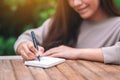 A beautiful woman writing on blank notebook on wooden table in the outdoors Royalty Free Stock Photo