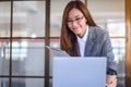 A beautiful young asian business woman drinking coffee and using laptop computer while working in office Royalty Free Stock Photo