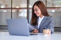 A beautiful young asian business woman drinking coffee and using laptop computer while working in office Royalty Free Stock Photo