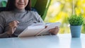 A beautiful young asian woman holding eye glasses while reading book Royalty Free Stock Photo