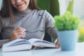 A beautiful young asian woman holding eye glasses while reading book Royalty Free Stock Photo