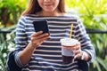 A beautiful young asian woman holding and using smart phone while drinking coffee Royalty Free Stock Photo