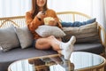 A beautiful young woman eating popcorn and searching channel with remote control to watch tv while sitting on Royalty Free Stock Photo