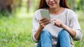 A beautiful young woman holding and using mobile phone in the park Royalty Free Stock Photo