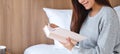 A beautiful young woman reading book in a white cozy bed at home Royalty Free Stock Photo