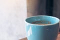 A blue mug of hot coffee on vintage wooden table in cafe Royalty Free Stock Photo