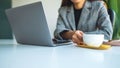 A business woman using and working on laptop computer while drinking coffee in office Royalty Free Stock Photo