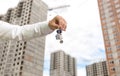 Closeup image of businessman hand holding keys from new home against houses under construction Royalty Free Stock Photo