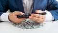 Closeup photo of businessman in suit with lots of money holding revolver in hands