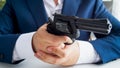 Closeup photo of businessman in suit sitting in office and holding revolver