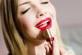 Closeup image of charming young blond woman beautiful girl with gorgeous makeup draws red lipstick