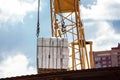 Closeup image of crane lifting heap of bricks at blue sky