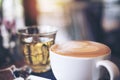 Closeup image of a cup of hot coffee and a tea glass on vintage wooden table Royalty Free Stock Photo