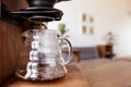 A drip coffee dropping into a beaker on wooden table