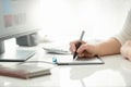 Closeup image of female graphic designer holding stylus and drawing on graphic tablet