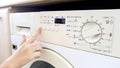 Closeup image of female hand pushing start button on washing machine Royalty Free Stock Photo