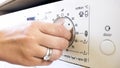 Closeup photo of female hand turning temperature controlling knob on washing machine Royalty Free Stock Photo