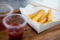 French fries in white paper plate with ketchup and chili sauce in plastic cups