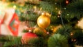 Closeup image of golden Christmas bauble hanging on fir tree at house living room against fireplace Royalty Free Stock Photo