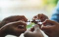 A group of people holding and putting a piece of white jigsaw puzzle together Royalty Free Stock Photo