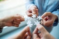 A group of people holding and putting a piece of white jigsaw puzzle together Royalty Free Stock Photo