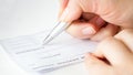 Closeup image of hand filling personal bank cheque with pen Royalty Free Stock Photo