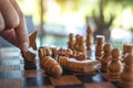 A hand holding and moving a horse to win another horse in wooden chessboard game Royalty Free Stock Photo