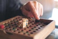 A hand playing wooden Snakes and Ladders game