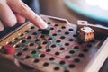 A hand playing wooden Snakes and Ladders game