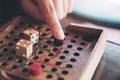 A hand playing wooden Snakes and Ladders game