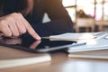 Hand pointing at a black tablet pc screen with notebook on wooden table Royalty Free Stock Photo