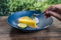 Closeup image of a hand scooping a yellow lemon curd cake to eat with fork and lemon juice Royalty Free Stock Photo