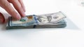 Closeup image of hand taking stack of dollars lying on hwite wooden desk Royalty Free Stock Photo