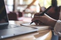 Hand writing down on a blank notebook with laptop on wooden table Royalty Free Stock Photo