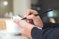 A hand writing down on a white blank notebook with coffee cup and dessert on table in cafe Royalty Free Stock Photo