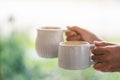 Hands holding two white cups of hot coffee with blurred nature background Royalty Free Stock Photo