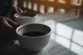 Hands holding two white cups of hot coffee on table in cafe Royalty Free Stock Photo